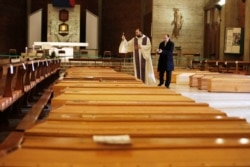 Don Marcello Crotti, left, blesses the coffins with Don Mario Carminati in the San Giuseppe church in Seriate, Italy, March 28, 2020.