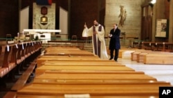 Don Marcello Crotti, left, blesses the coffins with Don Mario Carminati in the San Giuseppe church in Seriate, Italy, Saturday, March 28, 2020. The new coronavirus causes mild or moderate symptoms for most people, but for some, especially older…