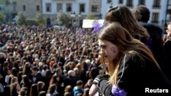 A woman with a female gender symbol on her cheek observes a demonstration for women's rights in Bilbao, Spain, March 8, 2018, on International Women's Day. 