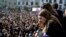 A woman with a female gender symbol on her cheek observes a demonstration for women's rights in Bilbao, Spain, March 8, 2018, on International Women's Day. 