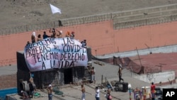 Inmates hold a sign that reads in Spanish "We want COVID-19 tests, we have the right to live"," as they gather ona roof during a prison protest at Lurigancho prison in Lima, Peru, April 28, 2020.