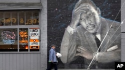 A man walks past a large mural of the Rev. Martin Luther King Jr. on the side of a diner, painted by artist James Crespinel in the 1990's and later restored, along Martin Luther King Jr. Way, Tuesday, April 3, 2018, in Seattle. 