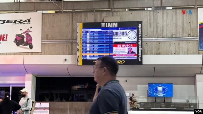 Un hombre pasa delante de un anuncio en pantalla con la foto del líder opositor Edmundo González y la frase “se busca” en el Aeropuerto Internacional Simón Bolívar de Maiquetía, el 3 de enero de 2025.