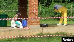 FILE - A health worker is sprayed with chlorine after visiting the isolation ward at Bikoro hospital, which received a new suspected Ebola case, in Bikoro, Democratic Republic of Congo, May 12, 2018. 