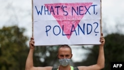 FILE - A participant holds up a placard reading "What's next Poland?" as demonstrators gather in front of the European institutions in Brussels to show their solidarity with Poland's LGBT community, Aug. 19, 2020. 