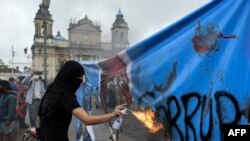 Un manifestante quema una pancarta con una fotografía de la Fiscal General de Guatemala, Consuelo Porras, durante una protesta exigiendo la renuncia del presidente guatemalteco Alejandro Giammattei, el 29 de julio de 2021. 