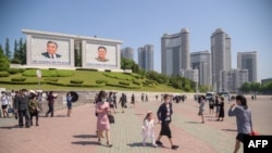 지난 19일 김일성, 김정일 부자의 초상화가 걸려 있는 북한 평양 시내를 시민들이 걷고 있다. 