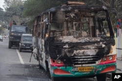 Indian army vehicles are parked behind a bus which was burnt by protesters during a protest against the Citizenship Amendment Bill in Gauhati, India, Dec. 13, 2019.