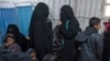 Two women (C), reportedly wives of Islamic State (IS) group fighters, wait with other women and children at a makeshift clinic at the Internally Displaced Persons (IDP) camp of al-Hol in al-Hasakeh governorate in northeastern Syria, Feb. 7, 2019. 