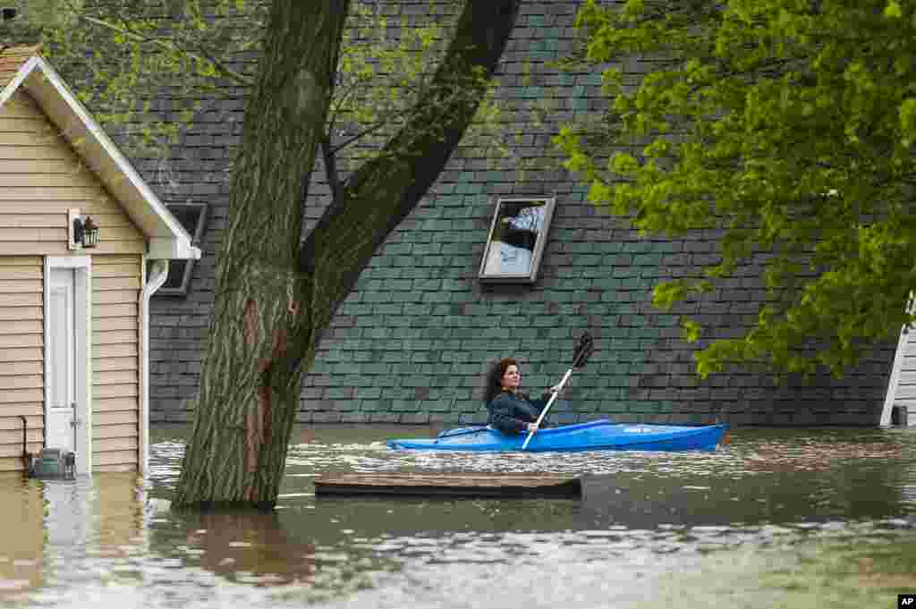 A woman use a kayak to assess the damage at homes in her neighborhood on Oakridge Road on Wixom Lake in Beaverton, Michigan. Rapidly rising water has overtaken dams and forced the evacuation of about 10,000 people from flooded communities in central Michigan. (Credit: Midland Daily News)&nbsp;