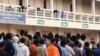 FILE - Multinational victims of scam centers, who were trafficked into working in Myanmar and were sent to Thailand on Feb. 12 amid a mounting crackdown on scam centers queue to get food as they wait for their embassies to pick them up, in Tak province, Thailand, Feb. 19, 2025. 