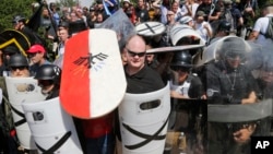 FILE - White nationalist demonstrators use shields as they guard the entrance to Lee Park in Charlottesville, Virginia, Aug. 12, 2017. 