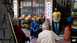 Men sit outside a grocery shop in Athens, June 5, 2020. The European Commission says Greece is likely to suffer deepest recession in the eurozone this year, but first quarter growth figures were better than expected.