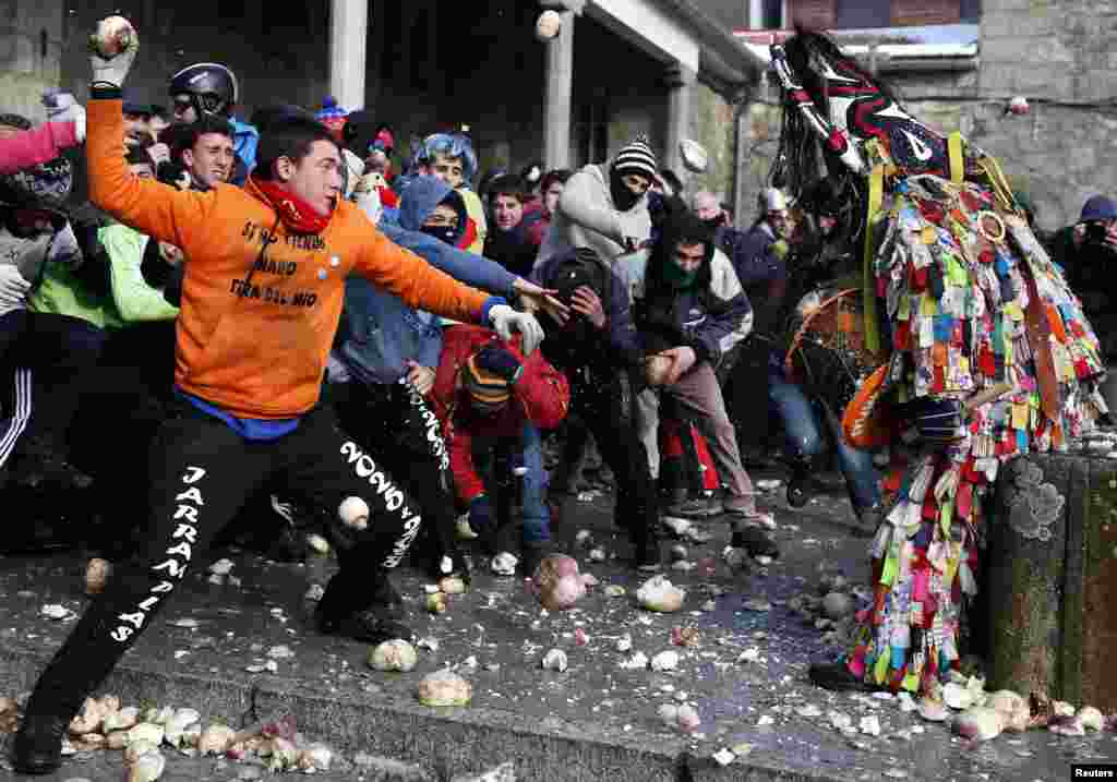 People throw turnips at the Jarramplas, a devil-like character, as he makes his way through the streets while beating his drum during the Jarramplas traditional festival in Piornal, southwestern Spain.
