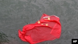 A Chinese flag floats on the surface it was thrown in the water by protesters during a demonstration in Hong Kong, Saturday, Aug. 3, 2019. 