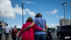 FILE - A woman and a senior citizen embrace as they walk out of a priority COVID-19 vaccination program for the elderly, in San Juan, Puerto Rico, Feb. 8, 2021. 