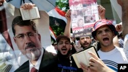 Para pendukung Presiden terguling Mesir, Mohmmed Morsi membawa poster Morsi dan kitab suci al-Quran dalam demonstrasi di Kairo, Senin (22/7). 