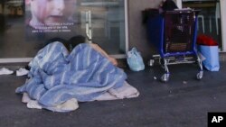 A homeless people sleep under blankets in front of the entrance of a bank, in Milan, Italy, Jan. 7, 2017. In Italy, subfreezing temperatures were blamed on the deaths of a half-dozen homeless people, while heavy snows and high winds resulted in re-routed flights, delayed ferries, canceled trains and closed roads.