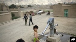 A girl prepares to fill a pitcher with water in a communal water pump in Kabul, Afghanistan.