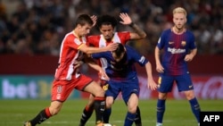 L’attaquant Lionel Messi, au centre, en duel avec les milieux de terrain de Gérone, Pere Pons, à gauche, et Alex Granell lors du match de football entre le FC Gérone et le FC Barcelone au stade Montilivi de Gérone le 23 septembre 2017. 