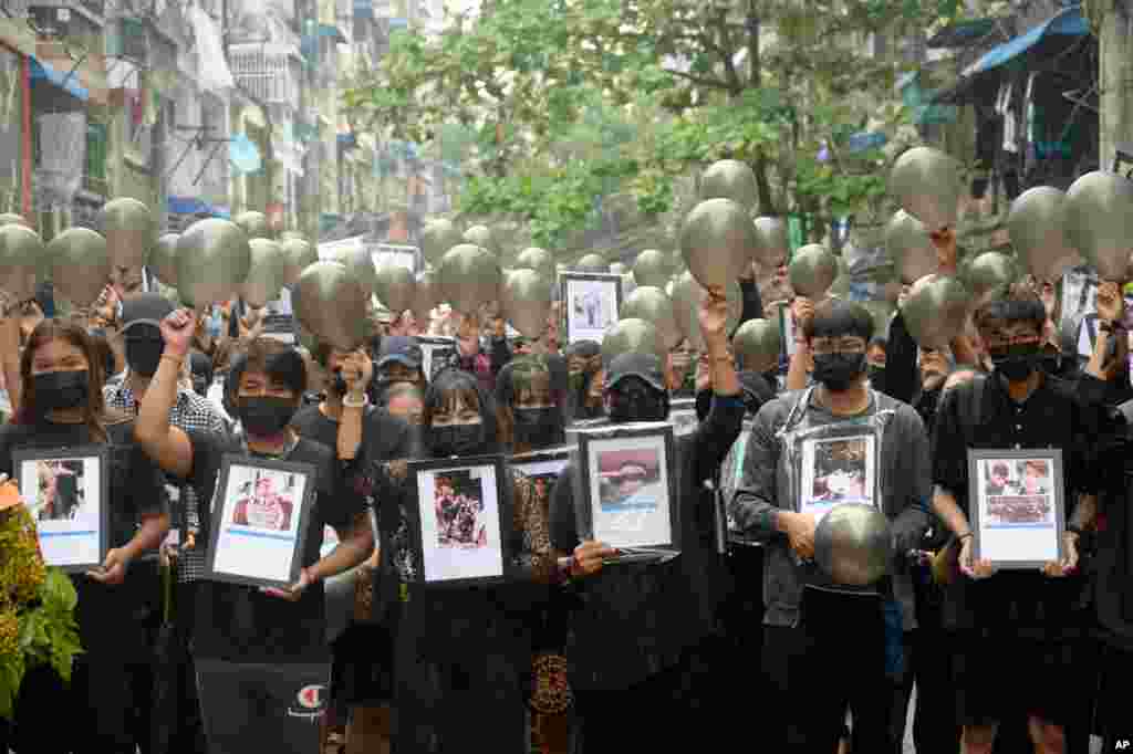 Anti-coup protesters holding pictures of those who died during a protest against the military offer them prayersin Yangon, Myanmar.