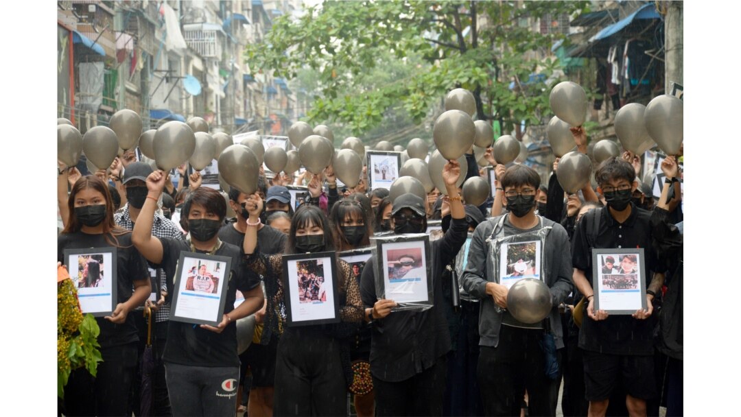 Anti-coup protesters holding pictures of those who died during a protest against the military offer them prayersin Yangon, Myanmar.