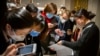 FILE - Journalists wearing face masks look at a government statement prior to a press conference about the coronavirus outbreak, in Beijing, China, Jan. 26, 2020.