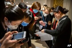 FILE - Journalists look at a government statement prior to a press conference about the coronavirus outbreak, in Beijing, China, Jan. 26, 2020. Meanwhile, citizen journalists are challenging the official narrative with their own reporting.