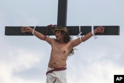 FILE—Ruben Enaje remains on the cross during the reenactment of Jesus Christ's sufferings as part of Good Friday rituals in San Pedro Cutud, north of Manila, Philippines, Friday, March 29, 2024.