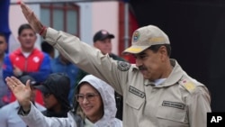 President Nicolas Maduro, and First Lady Cilia Flores wave to supporters during an event marking the 165th anniversary of the Battle of Santa Ines, in Caracas, Venezuela, Dec. 10, 2024.