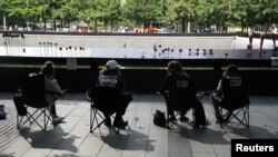 Familiares de víctimas de los ataques del 11 de septiembre de 2001, visitan la fuente sur del monumento erigido en el lugar donde estuvo el Centro Mundial de Comercio, en Nueva York, el 11 de septiembre de 2020.