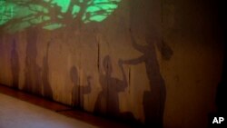 Dancers' shadows are cast on a stage backdrop during the contemporary dance production Ubuntu, at the Teresa Carreno Theater in Caracas, Venezuela, Dec. 4, 2018.