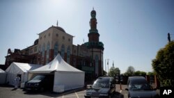 In this photo taken on Friday, April 24, 2020, a volunteer wearing protective clothing walks through the car park of Central Jamia Mosque Ghamkol Sharif in Birmingham, England, which has been transformed into a temporary morgue.