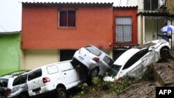 Mobil yang tersapu saat banjir yang dipicu oleh Badai Tropis Cristobal, terlihat tumpang tindih di Panchimalco, El Salvador, 3 Juni 2020.