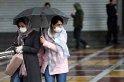 Women wear masks to protect themselves against the coronavirus, as they cross a street in Tehran, Iran, Feb. 25, 2020.