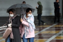 Women wear masks to protect themselves against the coronavirus, as they cross a street in Tehran, Iran, Feb. 25, 2020.