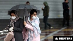 Women wear masks to protect themselves against the coronavirus, as they cross a street in Tehran, Iran, Feb. 25, 2020. 
