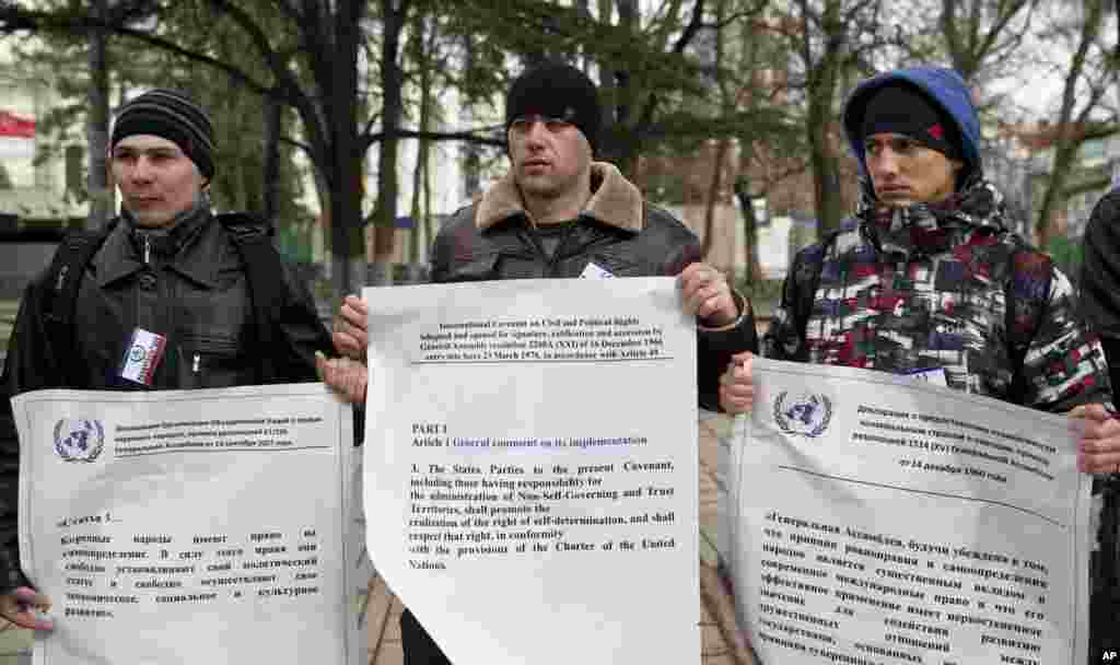 Manifestantes pró-Rússia seguram cópias gigantes dos documentos das Nações Unidas sobre o direito à auto-determinação, à porta do edifício do Parlamento regional em Simferopol, Crimeia, Ucrânia, Março 16, 2014. 