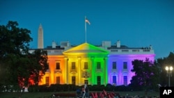 In this Friday, June 26, 2015 file photo, people gather in Lafayette Park to see the White House illuminated with rainbow colors in commemoration of the Supreme Court's ruling to legalize same-sex marriage in Washington. 