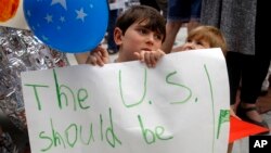 Shua Rich, de 6 años de edad, sostiene su letrero mientras protesta con su madre durante una manifestación contra las políticas de inmigración de EE. UU. frente a una oficina del representante Kevin Yoder, junio 22, 2018, en Overland Park, Kansas. 