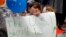 Shua Rich, de 6 años de edad, sostiene su letrero mientras protesta con su madre durante una manifestación contra las políticas de inmigración de EE. UU. frente a una oficina del representante Kevin Yoder, junio 22, 2018, en Overland Park, Kansas.