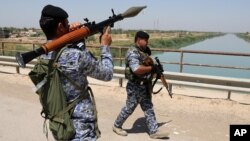 Iraqi federal policemen patrol in the town of Taji, about 20 kilometers (12 miles) north of Baghdad, June 26, 2014. 