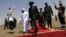 South Sudanese President Salva Kiir (C) walks with his Sudanese counterpart Omar al-Bashir (in white) before Kiir's departure from Khartoum, October 9, 2011. 