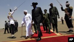 South Sudanese President Salva Kiir (C) walks with his Sudanese counterpart Omar al-Bashir (in white) before Kiir's departure from Khartoum, October 9, 2011. 