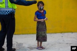 A child wearing a protective face mask, stands in line to receive a free meal in the Peronia neighborhood of Villa Nueva, Guatemala, July 24, 2020.