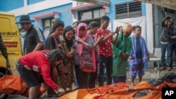 Beberapa warga berusaha mengidentifikasi jenazah untuk mencari anggota keluarganya yang masih hilang pasca tsunami di Pendeglang, Jawa Barat, Minggu (23/12). 