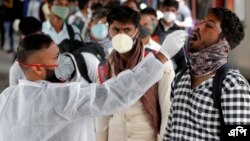 একজন স্বাস্থ্যকর্মী একটি ট্রেন স্টেশনে শহরে প্রবেশের অনুমতি দেয়ার আগে একজন ভ্রমণকারীর কাছ থেকে কোভিড-১৯ পরীক্ষা করার জন্য নমুনা সংগ্রহ করছেন। ১২ জানুয়ারী ২০২২। (ছবি-এপি/রাজনীশ কাকড়ে)