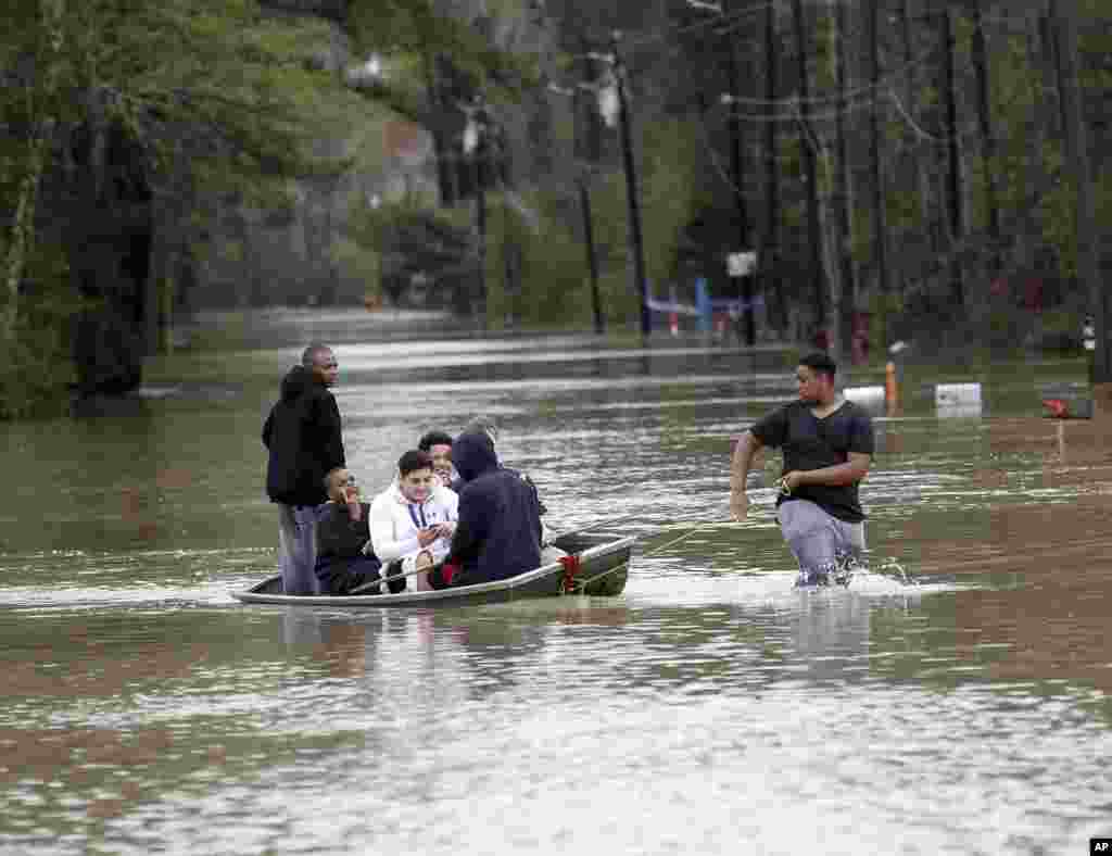 Seorang warga AS menarik perahu yang ditumpangi keluarganya saat mengungsi dari kawasan banjir di kota Independence, negara bagian Louisiana (11/3).
