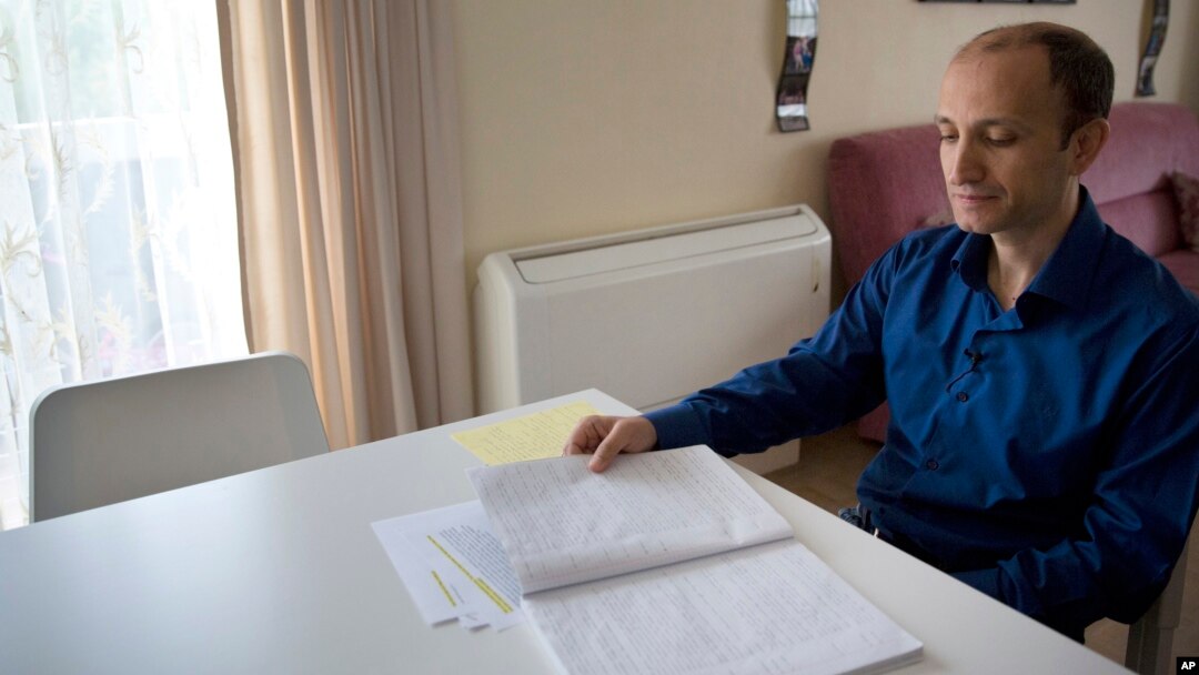 Cafer Topkaya, a former naval officer posted to NATO, looks at his diary, during an interview in his apartment in Brussels, Aug, 27, 2018. 