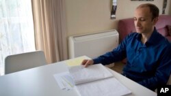 Cafer Topkaya, a former naval officer posted to NATO, looks at his diary, during an interview in his apartment in Brussels, Aug, 27, 2018. 